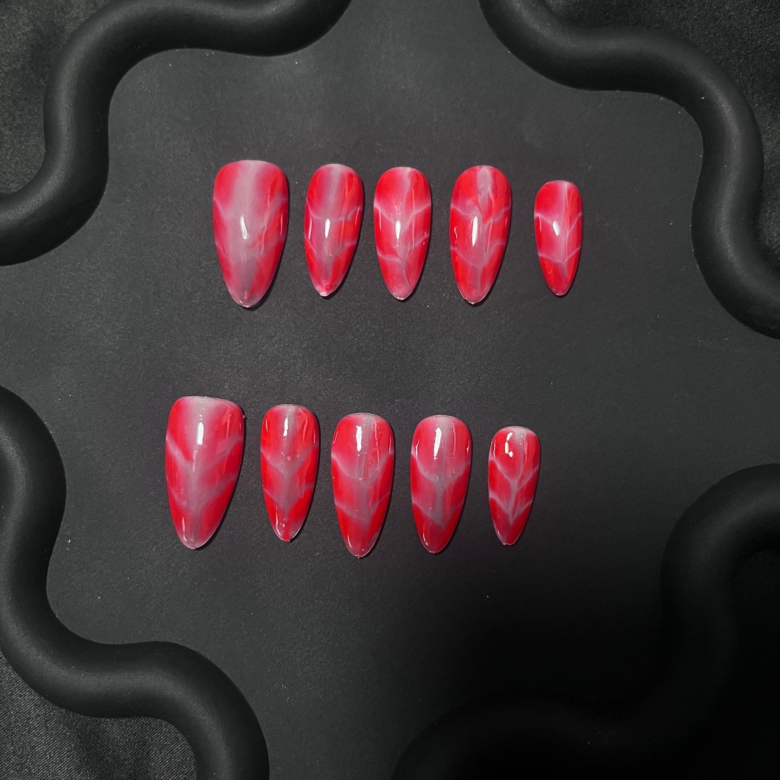 These almond-shaped nails feature a bold red and pink marble gradient design, adding a dynamic visual effect that is both elegant and eye-catching.